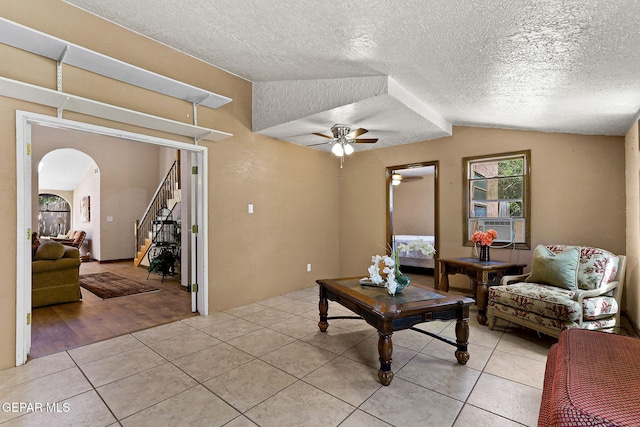630 Gary Ln, El Paso, TX 79922 - living room featuring arched walkways, ceiling fan, light tile patterned flooring, stairway, and a textured ceiling