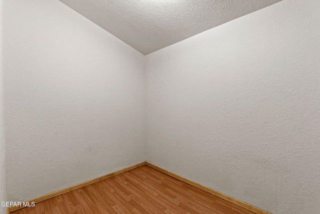 630 Gary Ln, El Paso, TX 79922 - empty room with baseboards, light wood-type flooring, vaulted ceiling, and a textured ceiling