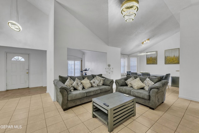 tiled living room with high vaulted ceiling, a textured ceiling, and a chandelier