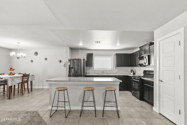 kitchen featuring a kitchen island, stainless steel fridge, black gas stove, and light tile patterned floors