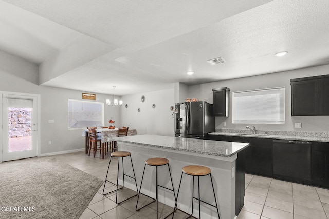 kitchen featuring a kitchen island, a breakfast bar, light tile patterned floors, stainless steel fridge with ice dispenser, and black dishwasher