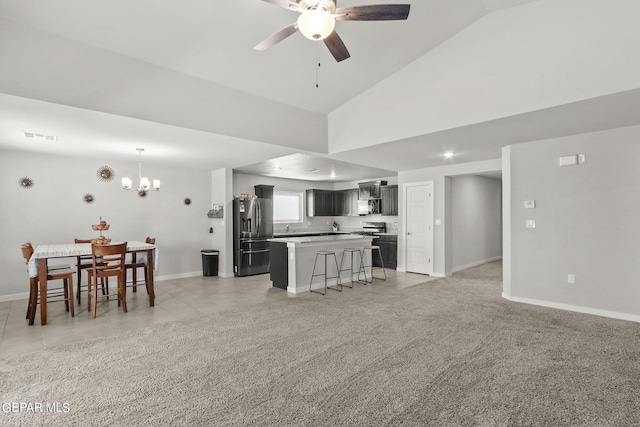 living room featuring high vaulted ceiling, ceiling fan with notable chandelier, and light carpet