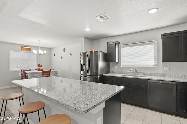 kitchen with decorative light fixtures, stainless steel refrigerator with ice dispenser, a kitchen island, sink, and black dishwasher