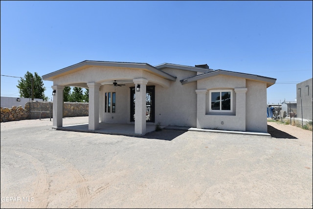 view of front facade with a ceiling fan, a patio area, fence, and stucco siding