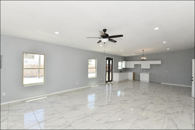 tiled spare room featuring sink and ceiling fan with notable chandelier