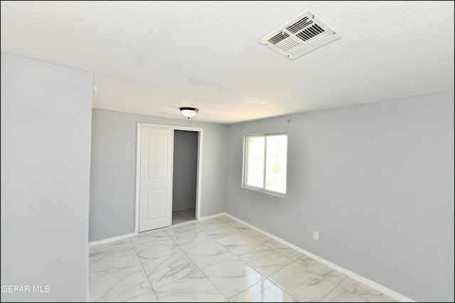 spare room with a textured ceiling and light tile patterned flooring