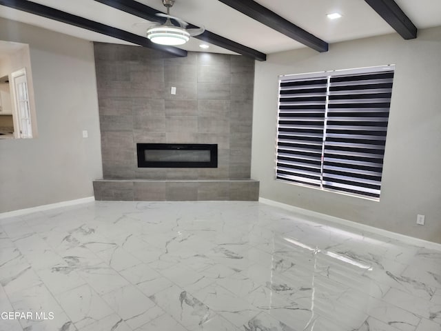 unfurnished living room featuring ceiling fan, beam ceiling, a tile fireplace, and tile patterned flooring