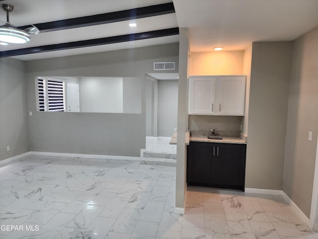 interior space featuring beamed ceiling, sink, light tile patterned flooring, and white cabinetry