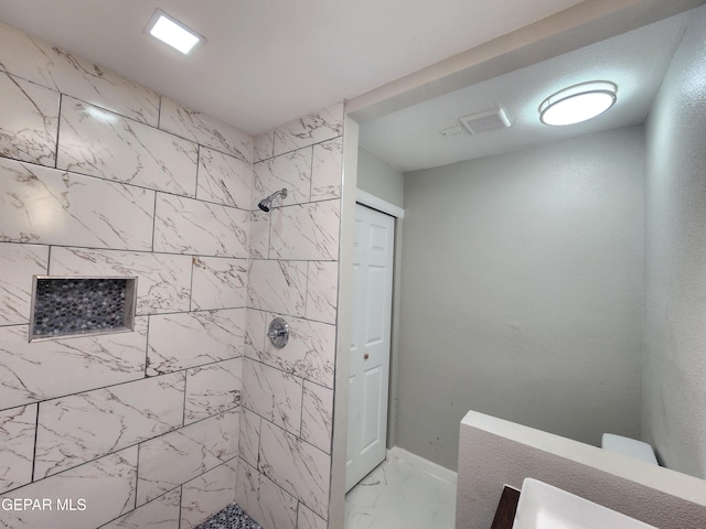 bathroom featuring tile patterned flooring and tiled shower