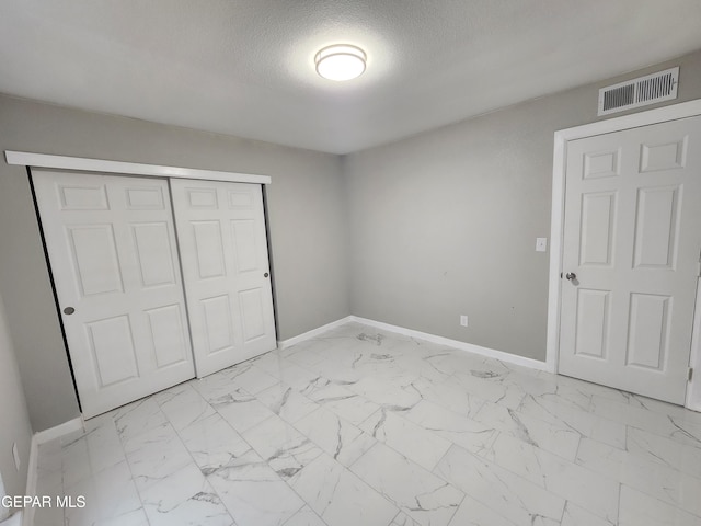 unfurnished bedroom featuring a textured ceiling, a closet, and light tile patterned floors