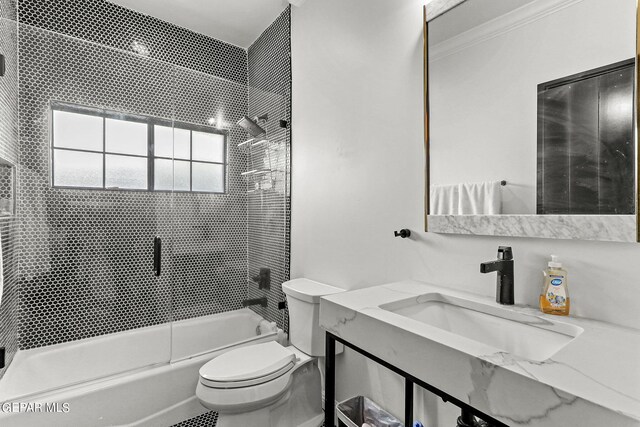 full bathroom featuring combined bath / shower with glass door, crown molding, vanity, and toilet