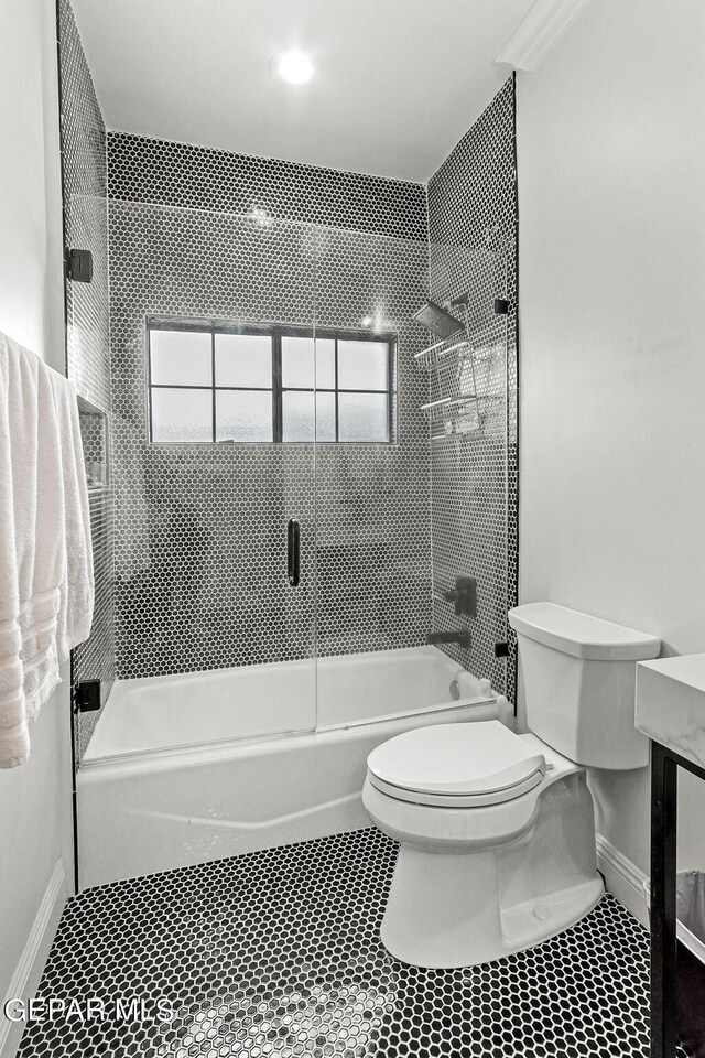 bathroom featuring combined bath / shower with glass door, toilet, and tile patterned floors