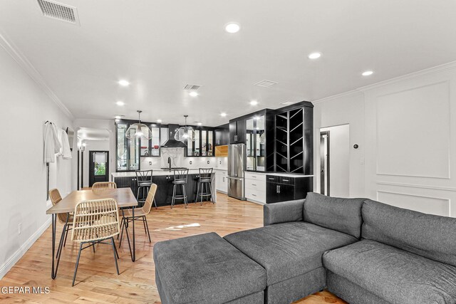 living room with ornamental molding, light wood-type flooring, and sink