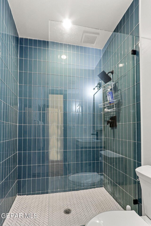 bathroom featuring tiled shower and toilet