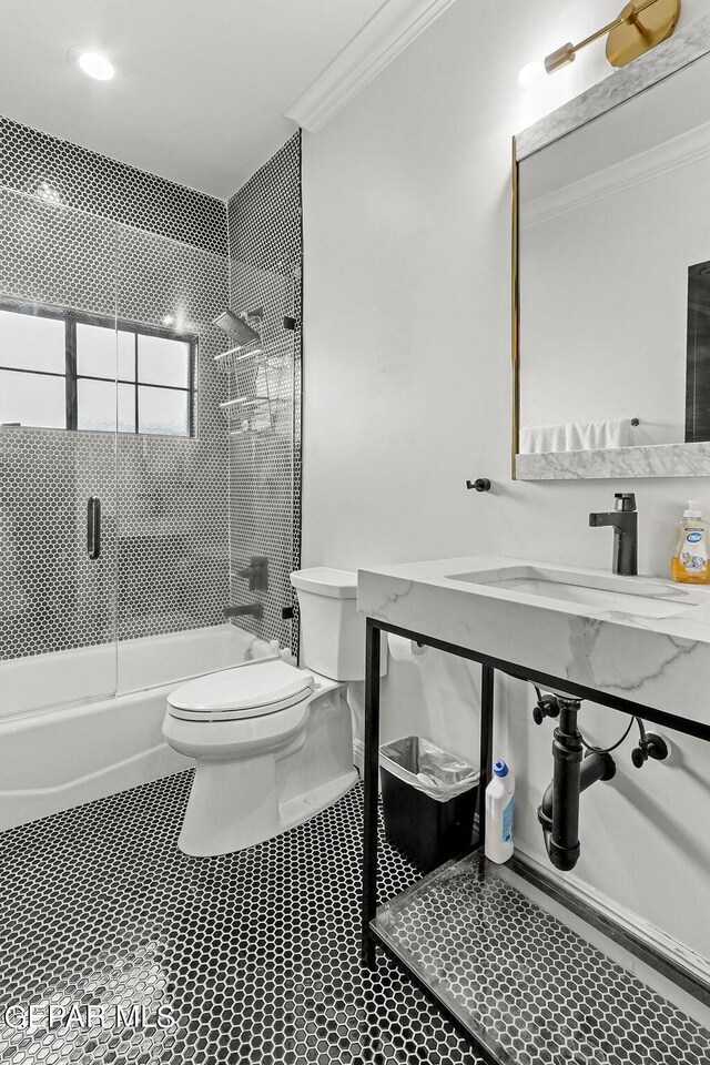 full bathroom with combined bath / shower with glass door, crown molding, vanity, and toilet