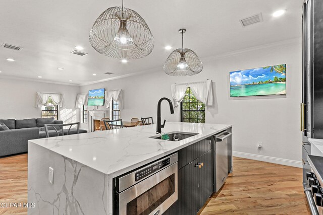 kitchen featuring an island with sink, hanging light fixtures, sink, and a wealth of natural light