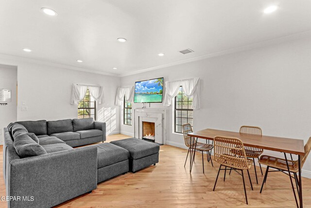 living room featuring light hardwood / wood-style flooring, ornamental molding, a high end fireplace, and a wealth of natural light