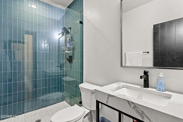 bathroom with a tile shower, vanity, and toilet