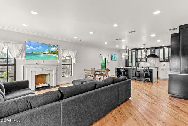 living room with light hardwood / wood-style floors, crown molding, and a fireplace