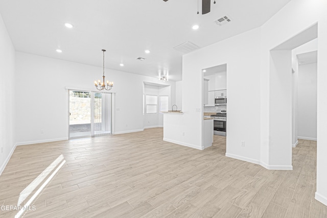 unfurnished living room featuring light wood-style flooring, recessed lighting, ceiling fan with notable chandelier, visible vents, and baseboards