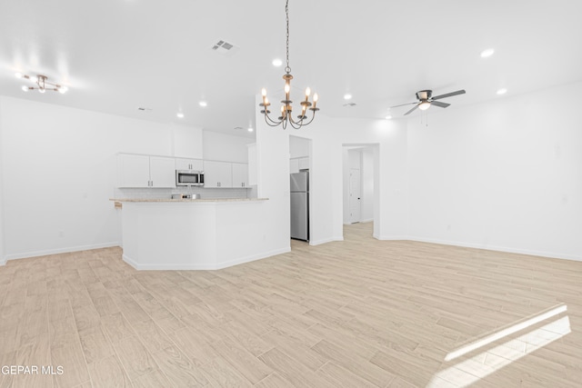 kitchen featuring light wood-type flooring, ceiling fan with notable chandelier, white cabinetry, appliances with stainless steel finishes, and decorative light fixtures