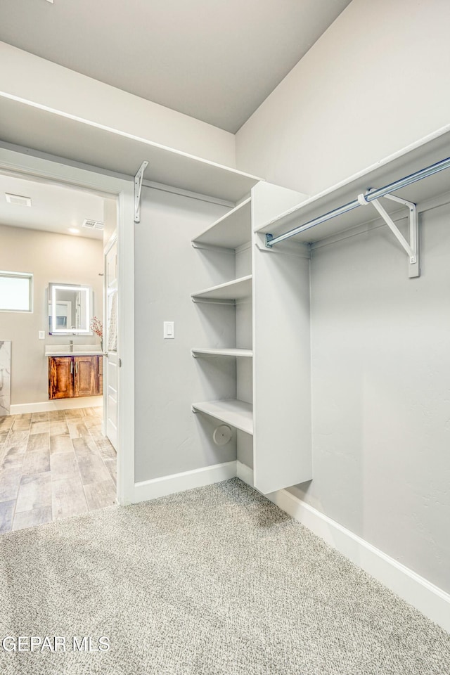 walk in closet featuring light colored carpet