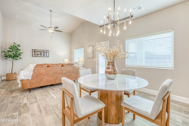 dining room featuring ceiling fan with notable chandelier, light hardwood / wood-style floors, and vaulted ceiling