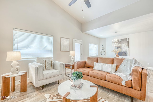 living room with ceiling fan with notable chandelier, light wood-type flooring, and high vaulted ceiling