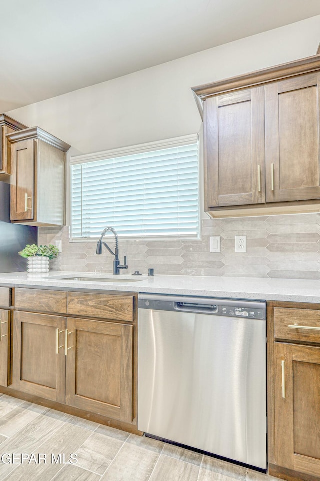 kitchen featuring decorative backsplash, light stone countertops, light wood-type flooring, sink, and dishwasher