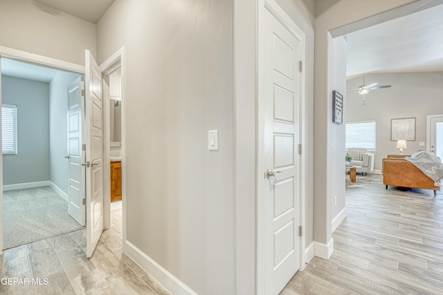 hallway with light hardwood / wood-style floors and vaulted ceiling