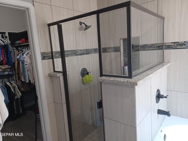 bathroom with tile walls, independent shower and bath, and tile patterned floors