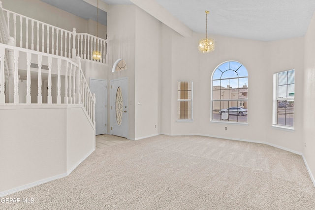 foyer featuring light colored carpet, a notable chandelier, and high vaulted ceiling