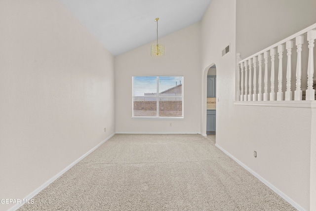 carpeted spare room with high vaulted ceiling