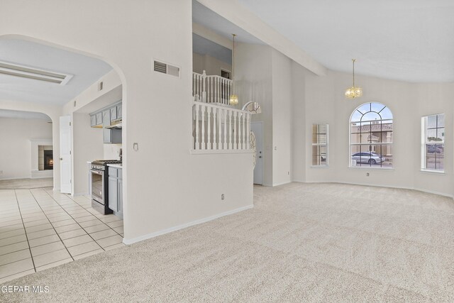 unfurnished living room with light carpet, beamed ceiling, and high vaulted ceiling