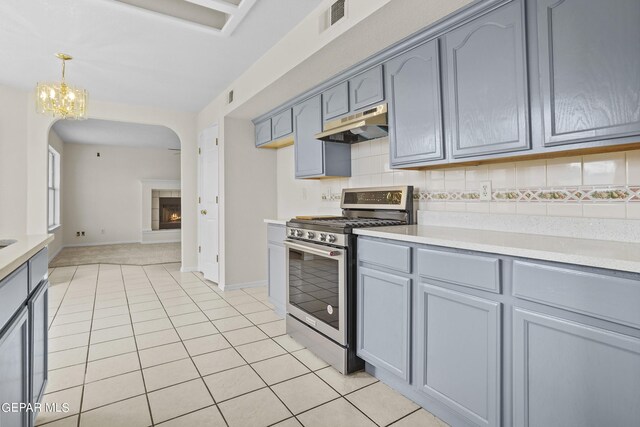 kitchen featuring hanging light fixtures, light tile patterned floors, stainless steel range oven, a chandelier, and tasteful backsplash