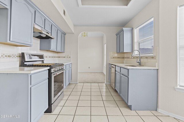 kitchen with appliances with stainless steel finishes, backsplash, light tile patterned flooring, and sink