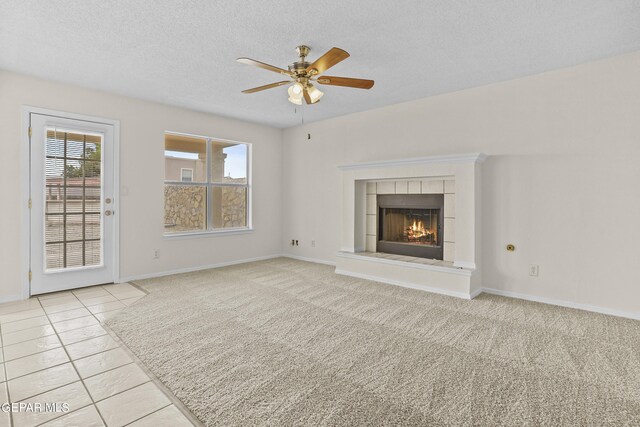 unfurnished living room featuring ceiling fan, a fireplace, light carpet, and a textured ceiling