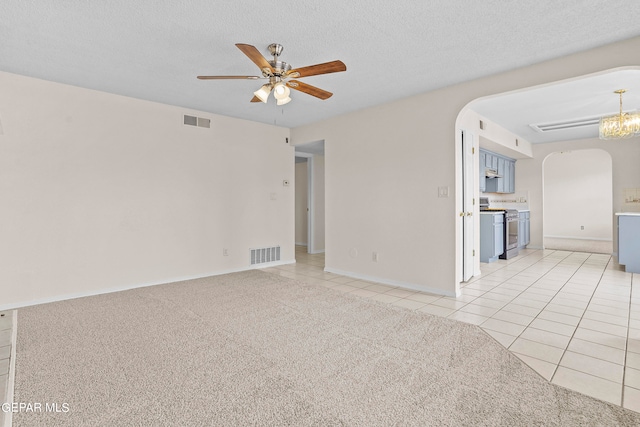 unfurnished living room featuring ceiling fan with notable chandelier, light carpet, and a textured ceiling