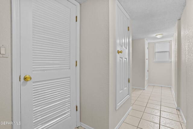 corridor featuring a textured ceiling and light tile patterned floors