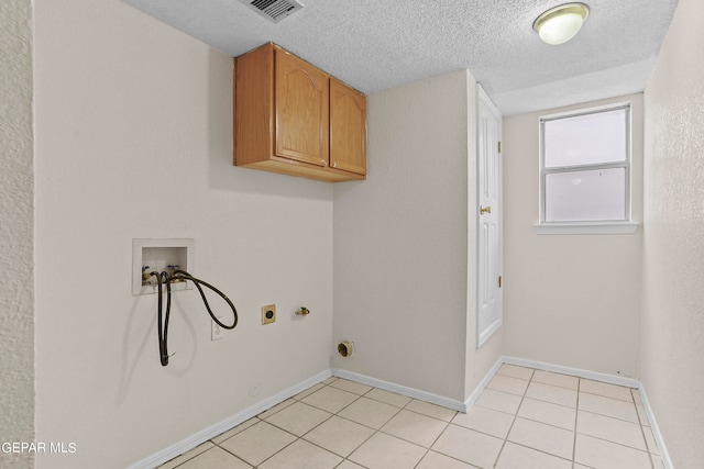 washroom with light tile patterned floors, hookup for an electric dryer, washer hookup, cabinets, and a textured ceiling