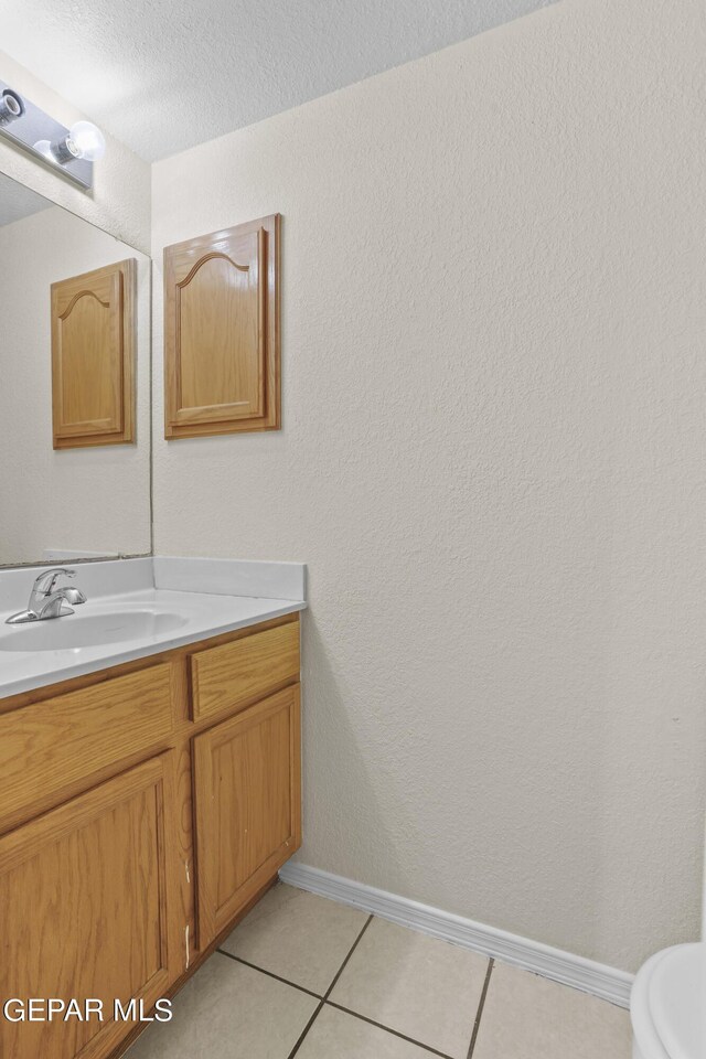 bathroom with vanity, a textured ceiling, toilet, and tile patterned floors