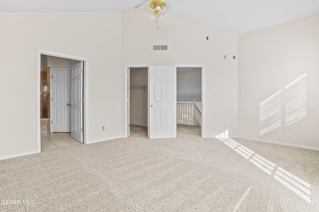 unfurnished bedroom with high vaulted ceiling, ensuite bath, a closet, a spacious closet, and light colored carpet