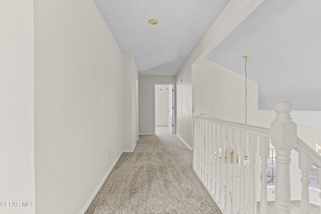 hall with light carpet and a textured ceiling