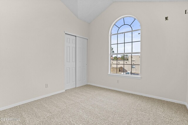 unfurnished room featuring carpet and vaulted ceiling