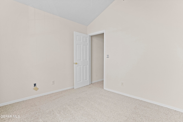 spare room featuring lofted ceiling and light colored carpet