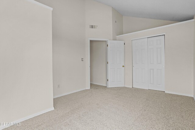 unfurnished bedroom with a closet, light colored carpet, and vaulted ceiling