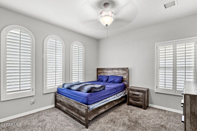 carpeted bedroom with multiple windows and ceiling fan