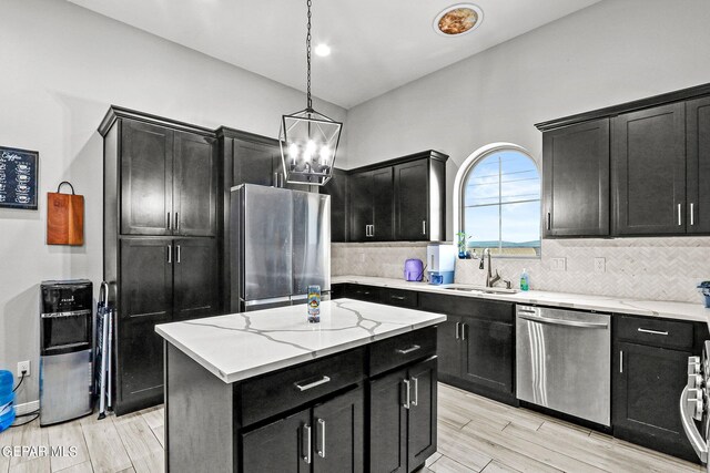 kitchen featuring a kitchen island, light hardwood / wood-style flooring, appliances with stainless steel finishes, hanging light fixtures, and sink