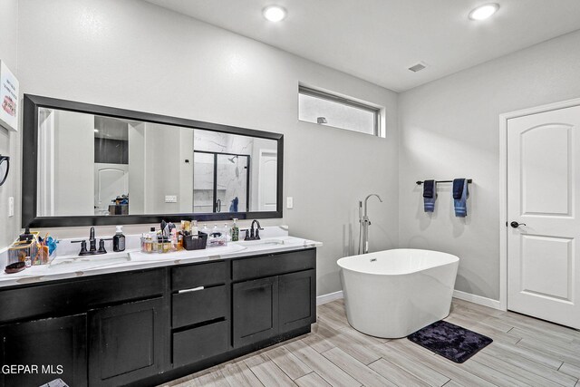 bathroom with hardwood / wood-style floors, independent shower and bath, and vanity