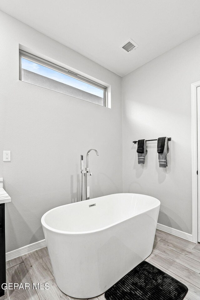 bathroom with a wealth of natural light, a tub, and hardwood / wood-style floors